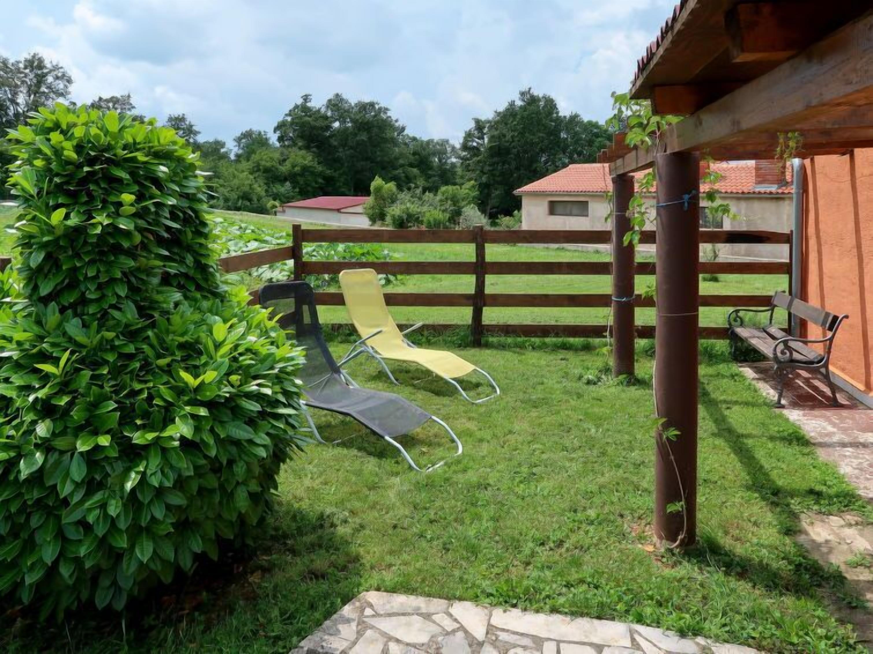 Un espace patio agrémenté d’une clôture en bois, de deux chaises de jardin et d’un chemin pavé de pierres.