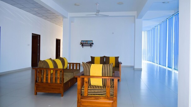 A spacious room with a high ceiling, a ceiling fan, and a large window providing natural light. - Catamaran 6 Guest Inn (Trincomalee)