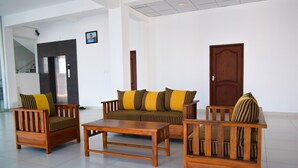 A modern lobby with a sofa set, a coffee table, and a wooden chair. - Catamaran 6 Guest Inn (Trincomalee)
