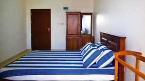 A bedroom with a bed, wooden wardrobe, and a door. - Catamaran 6 Guest Inn (Trincomalee)