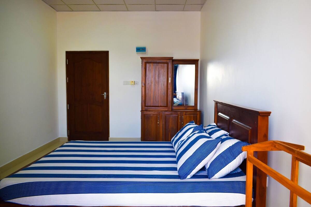 A bedroom with a bed, wooden wardrobe, and a door.