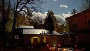 A rustic outdoor area with stone flooring, a small wooden table, and several lit candles. - Romantic Couples Getaway - Sauna, Hot Tub, Private Beach access, Hiking trails (Lambton Shores)