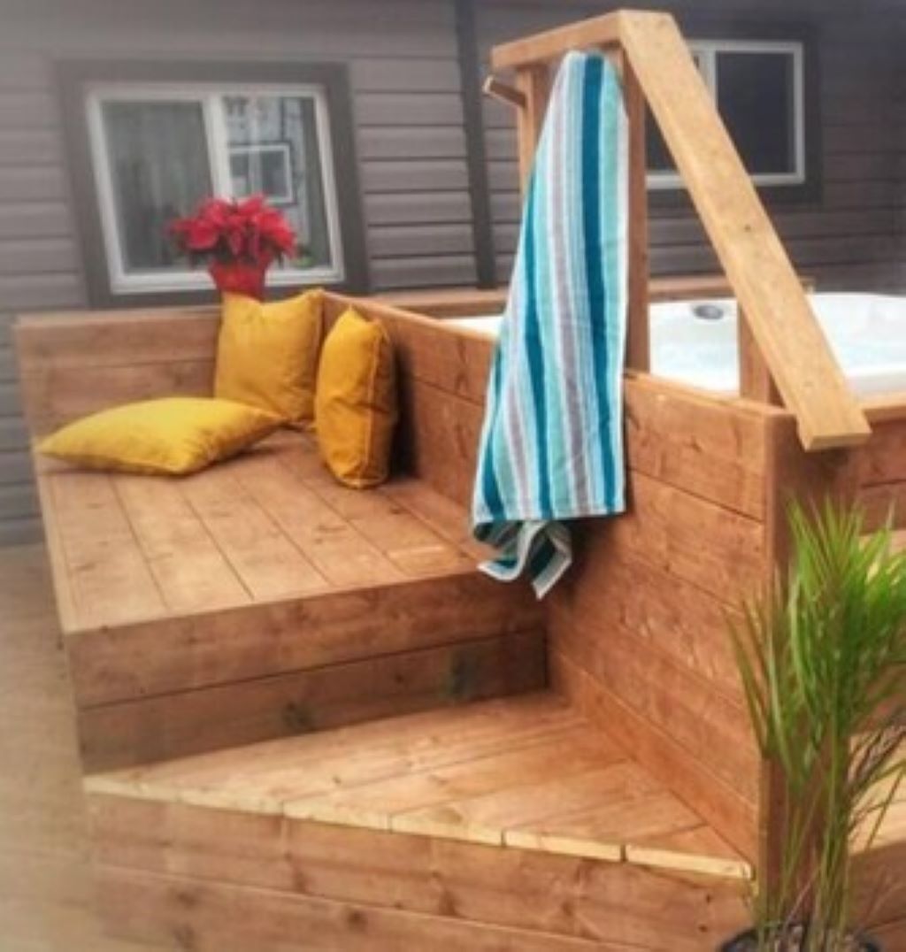 Zona salotto esterna in legno con cuscini e un asciugamano a righe.