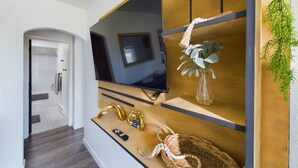 Een moderne woonkamer met een flatscreen televisie, houten planken en een plant.