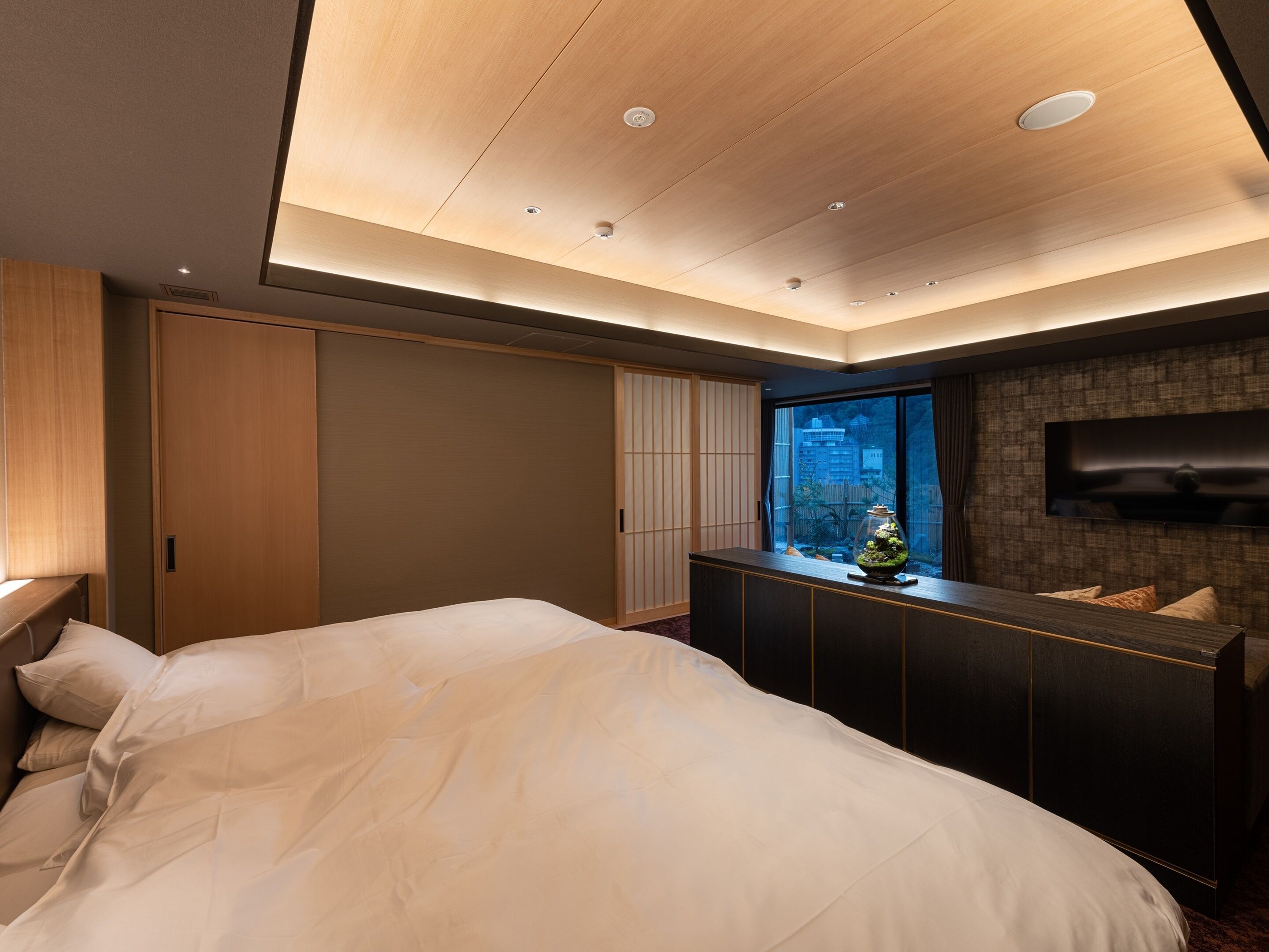 Une chambre moderne avec un lit, une commode, un téléviseur et une fenêtre donnant sur un beau paysage.