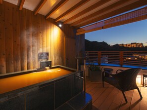 A wooden spa area with a hot tub, a sign, and a view of a building across a body of water. - Arima Onsen ShikinoIrodori Hatago (Kobe)