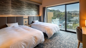 Une chambre d’hôtel moderne avec deux lits, une grande fenêtre donnant sur la ville et un plafond en bois.