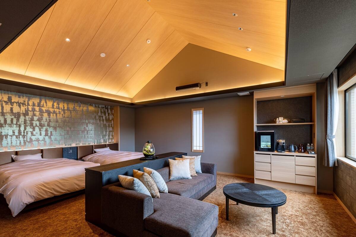 Een moderne hotelkamer met een groot bed, een bank, een tafeltje en een kitchenette.