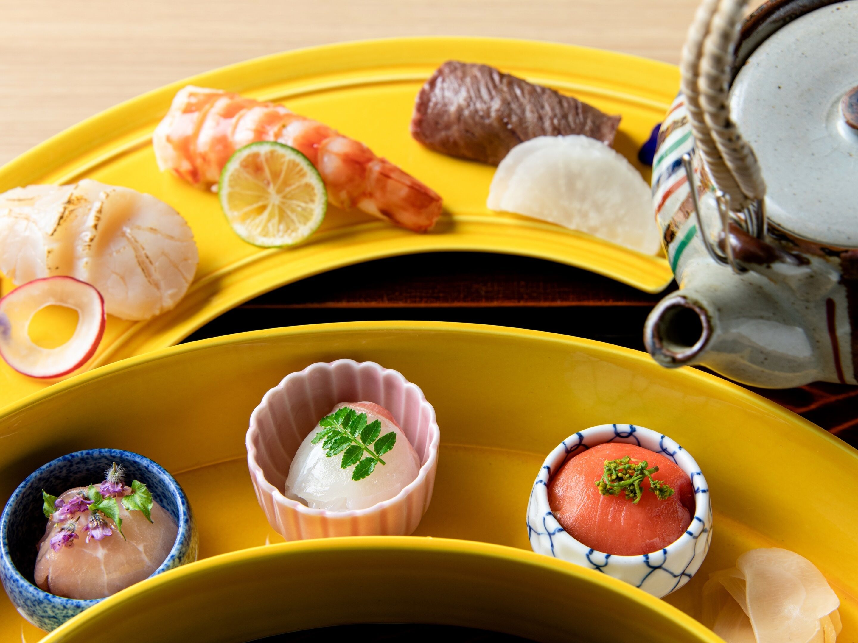 Eine gelbe Tablett mit verschiedenen Speisen, darunter Garnelen, Sashimi und eine Schüssel Suppe.