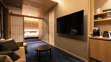 A hotel room with a bed, a TV, a coffee machine, and a small table.