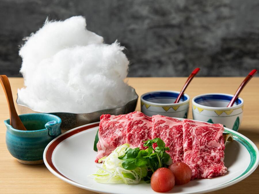 A plate of raw meat with vegetables and a bowl of cotton candy.