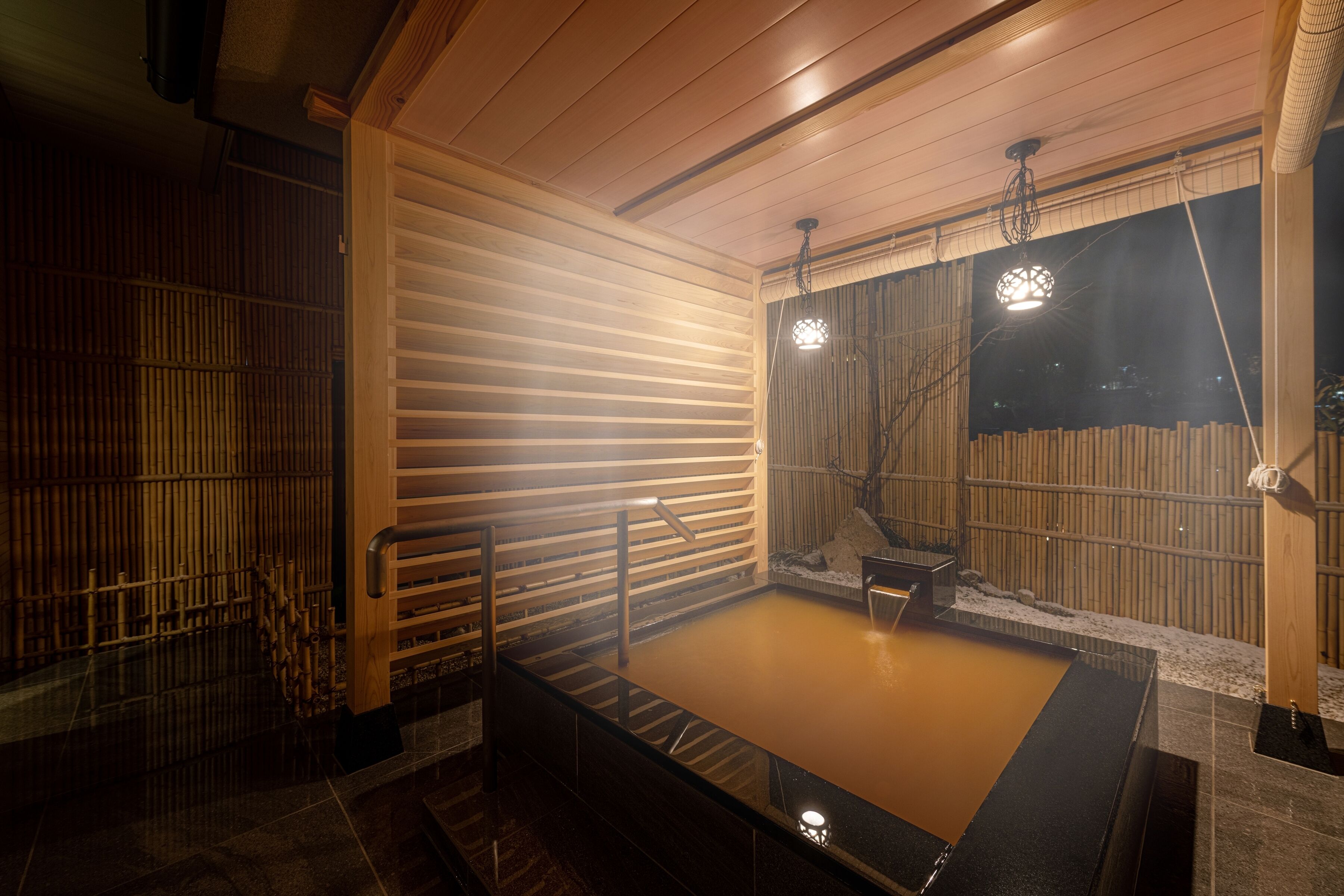 Un onsen japonais traditionnel, avec un intérieur en bois, un bain en pierre et une clôture en bambou.