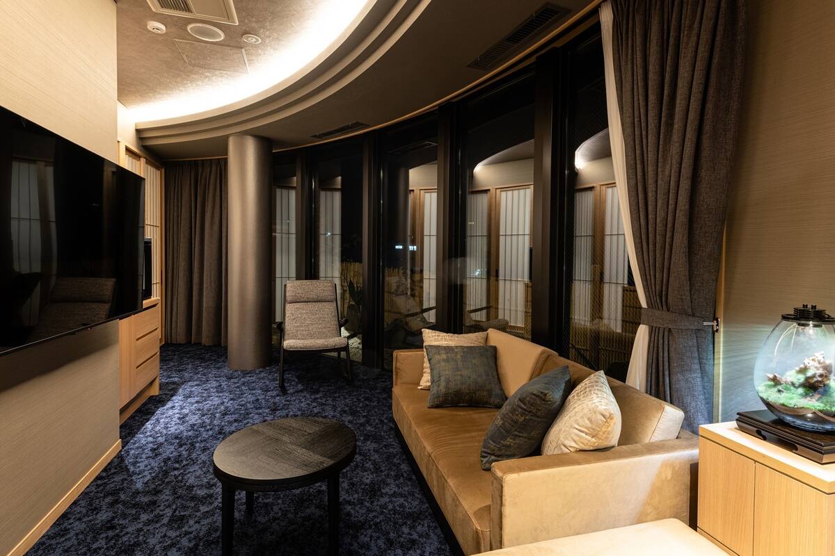 Een moderne, goed verlichte kamer met een bank, fauteuil en een klein rond tafeltje.