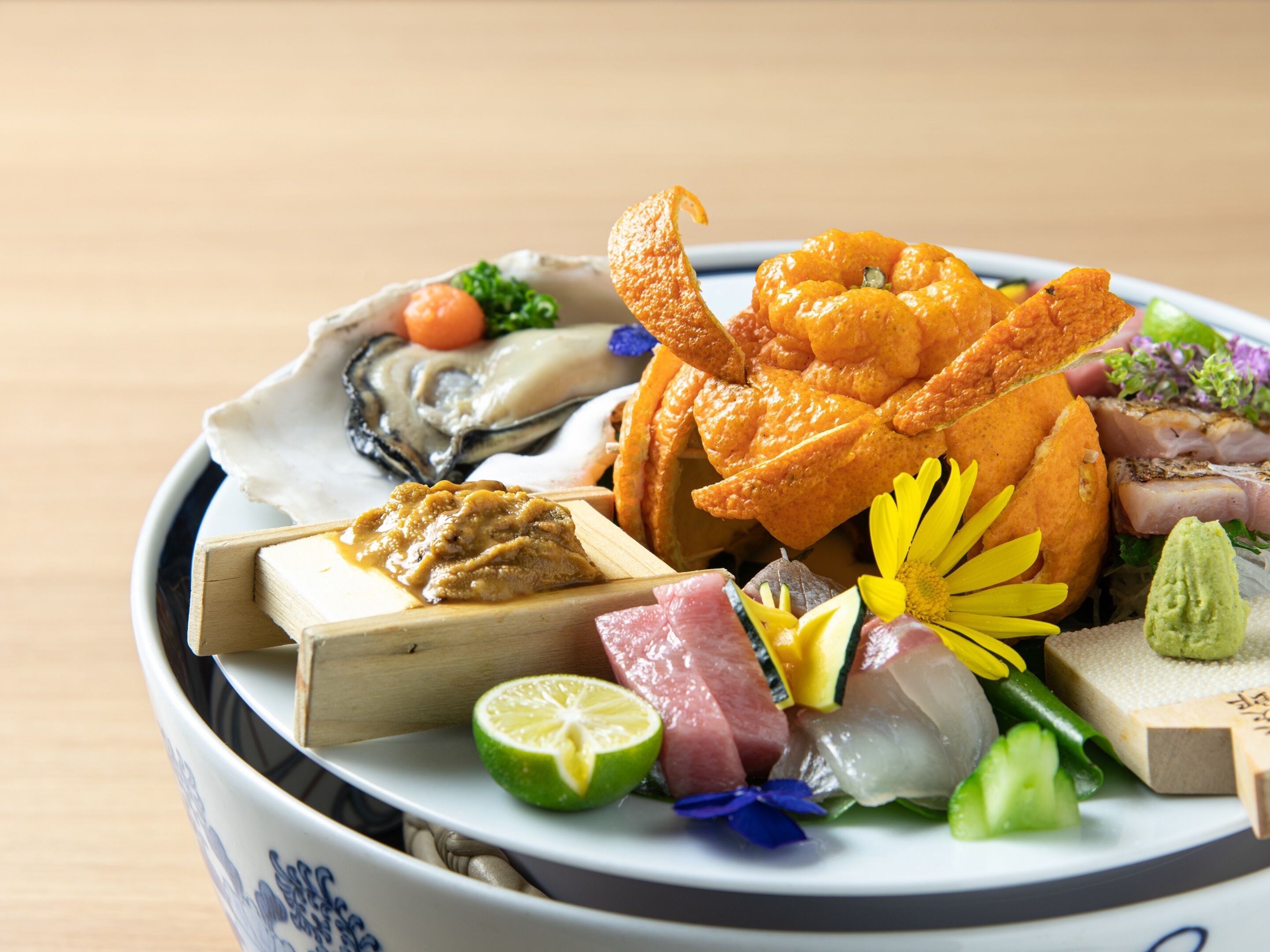 Un bol contenant un assortiment de fruits de mer et de légumes, notamment des huîtres, des crevettes et une tranche de citron vert.