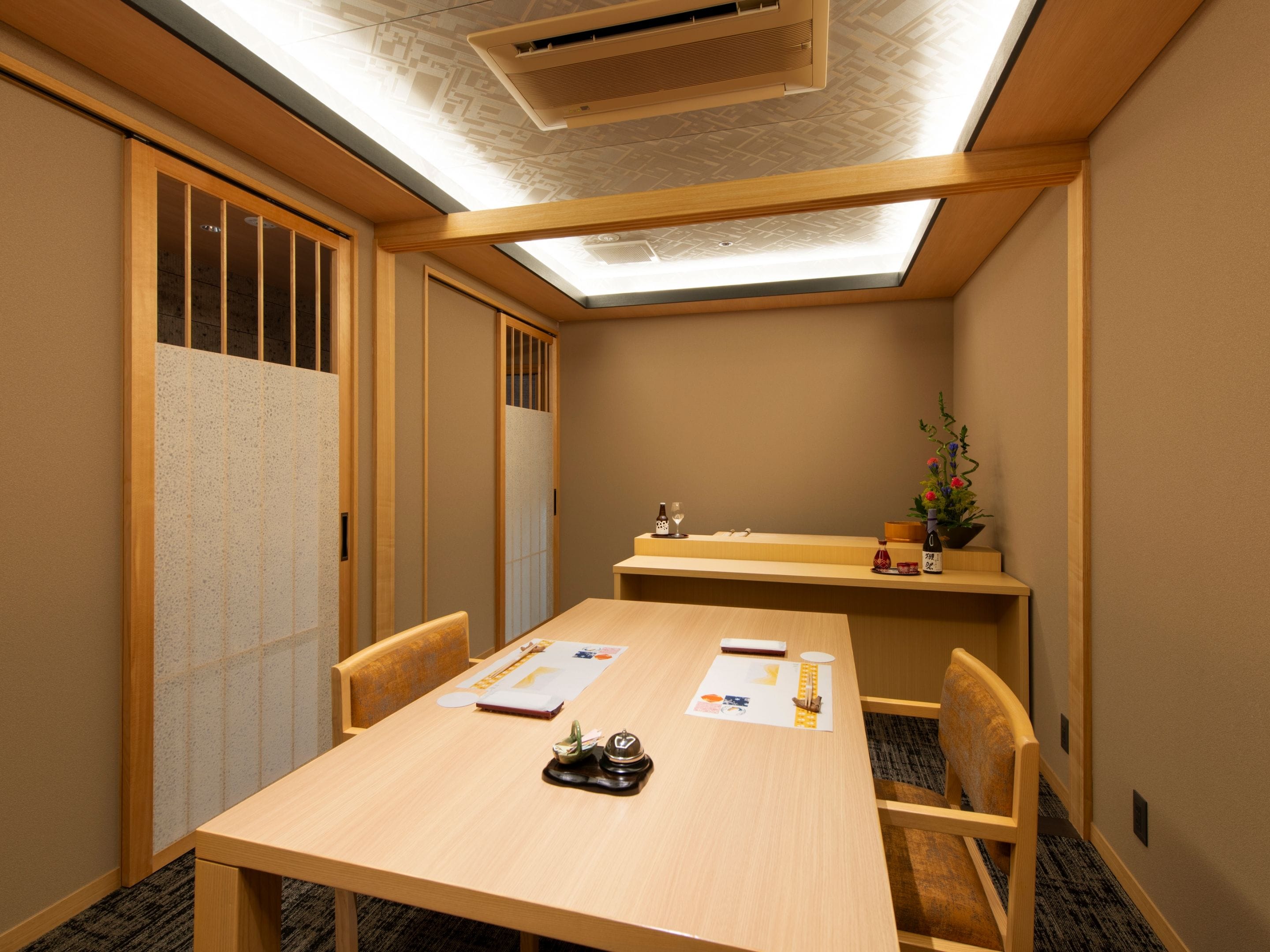 A conference room with a long table, chairs, a small desk, and a plant.