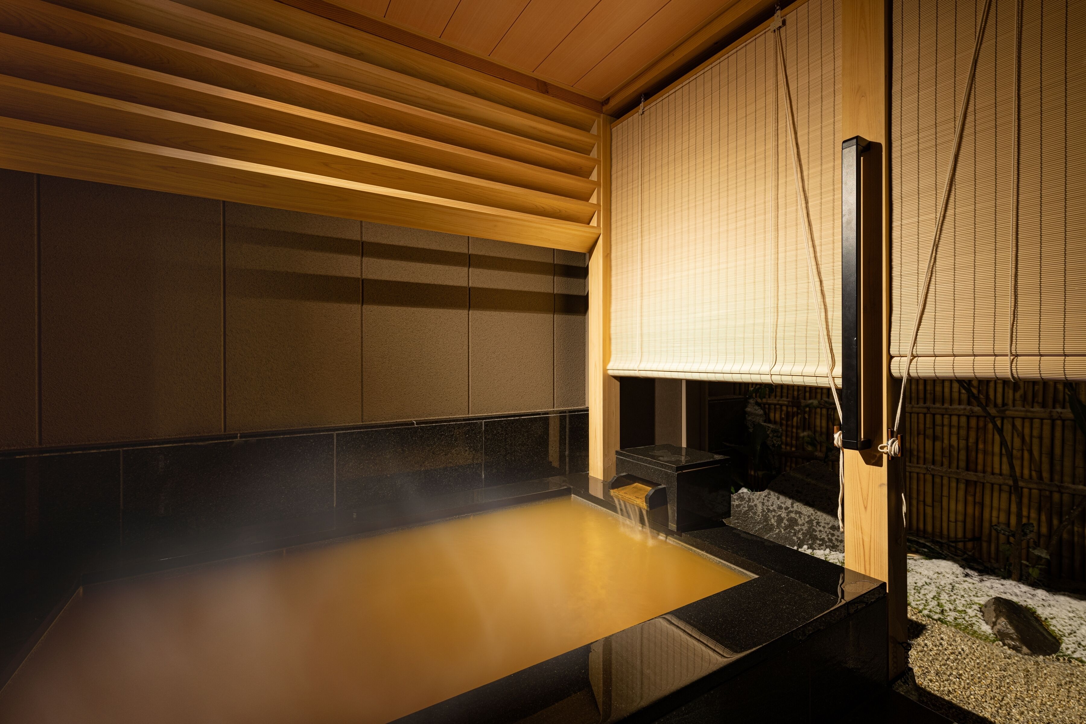 A traditional Japanese onsen with a wooden ceiling, tiled walls, and a wooden bench.
