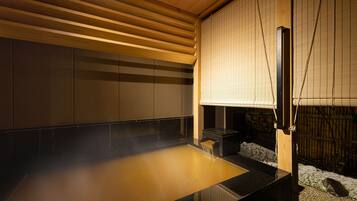 A traditional Japanese onsen with a wooden ceiling, tiled walls, and a wooden bench.