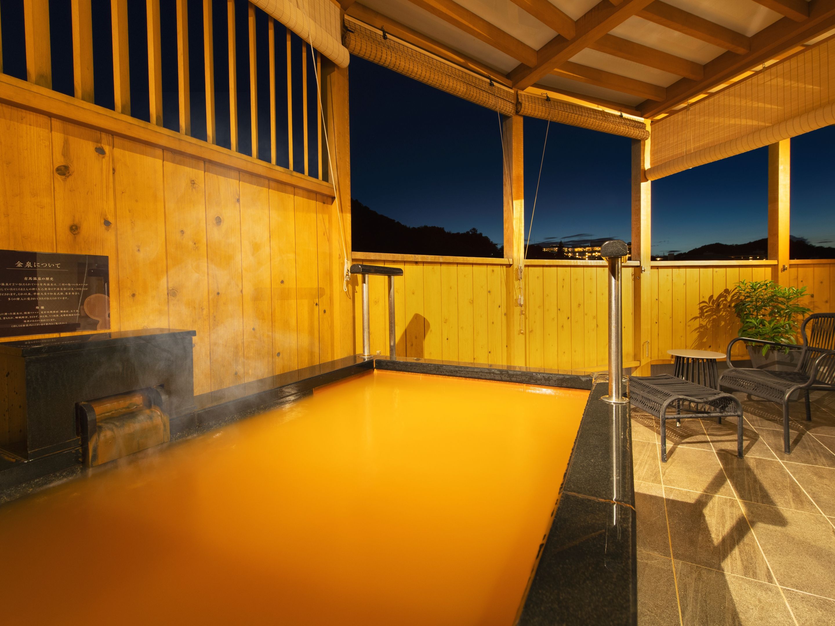 Ein Whirlpool mit einer Holzterrasse, einem Metallgeländer und Blick auf den Nachthimmel.