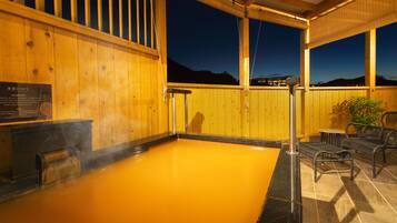 Ein Whirlpool mit einer Holzterrasse, einem Metallgeländer und Blick auf den Nachthimmel.
