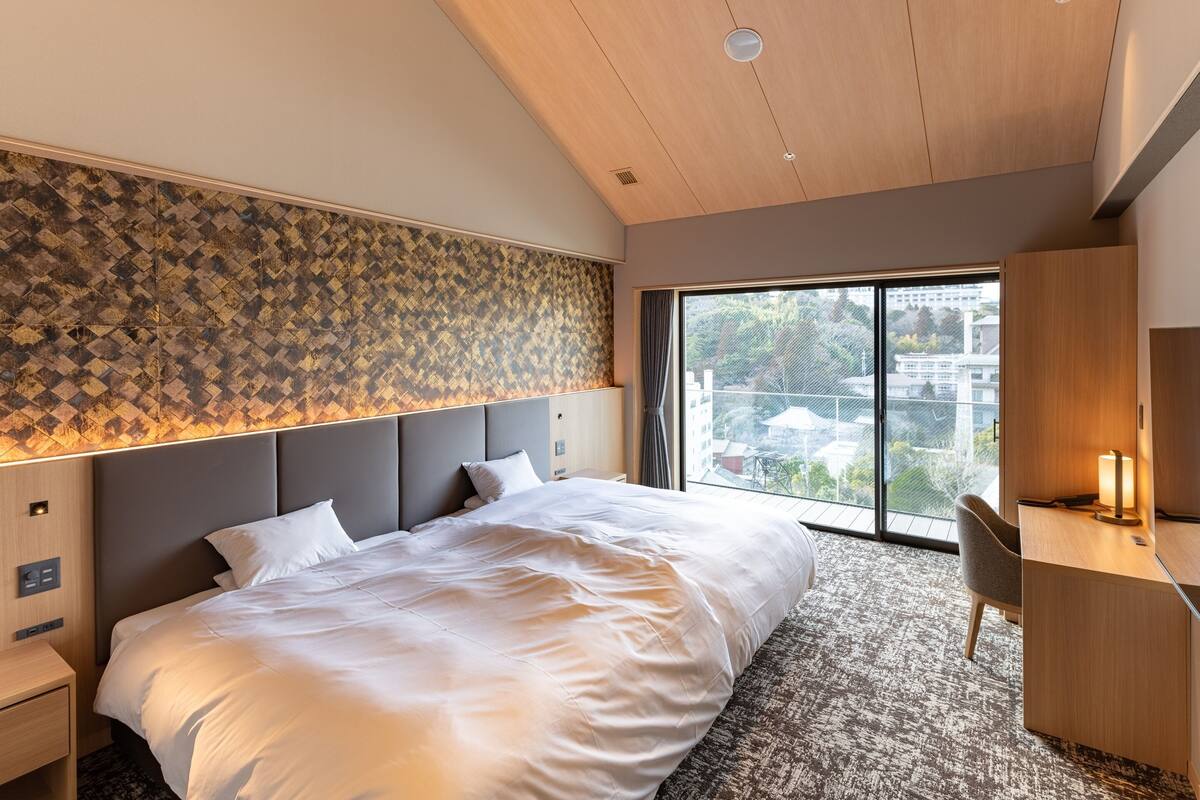 Een moderne hotelkamer met een groot bed, een bureau en uitzicht op de stad.