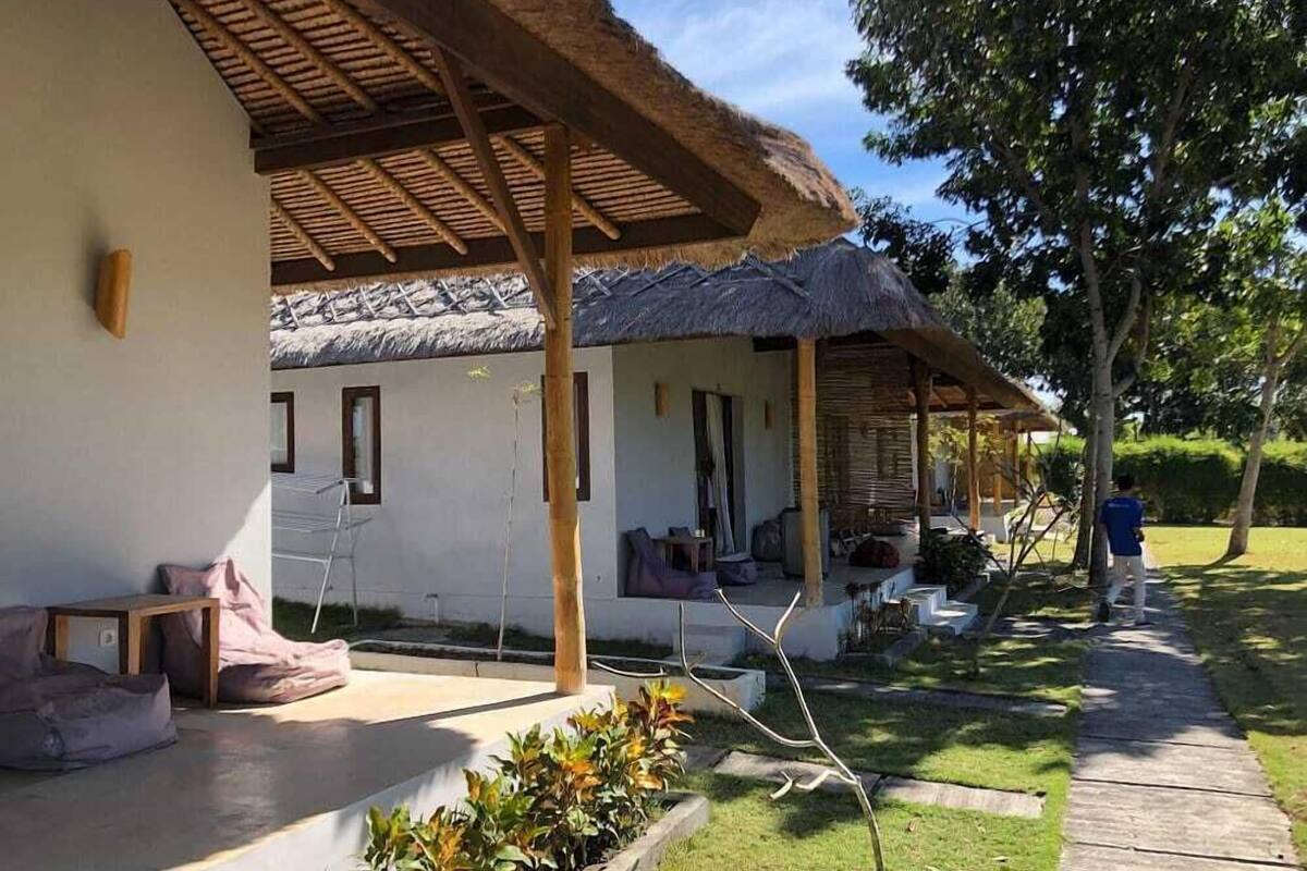 A bungalow with a thatched roof, outdoor seating, and a garden area.