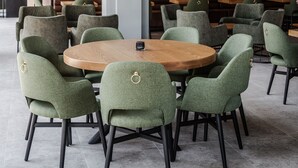 A dining area with round tables and green upholstered chairs.