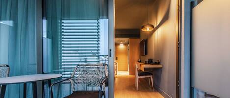 Una habitación de hotel moderna con una puerta de vidrio que da a un comedor, una silla y una mesa.