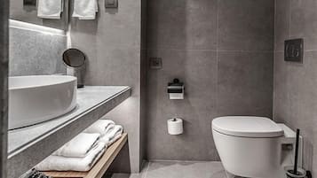 Un baño moderno con un lavamanos grande, espejo y retrete.