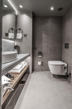 A modern bathroom with a large sink, mirror, and toilet.