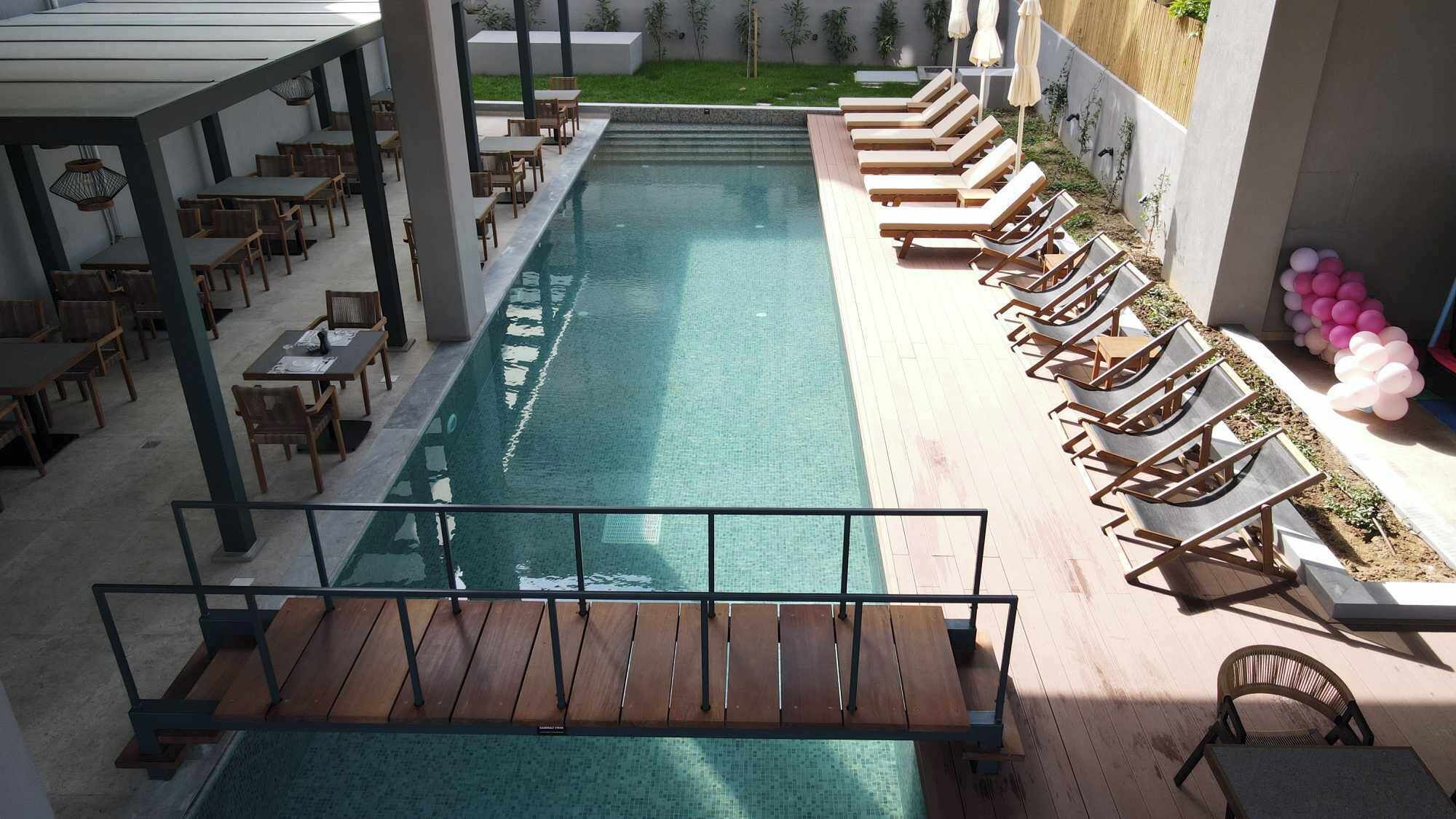 Un espace piscine aménagé avec des chaises longues, des tables et un coin salon abrité.
