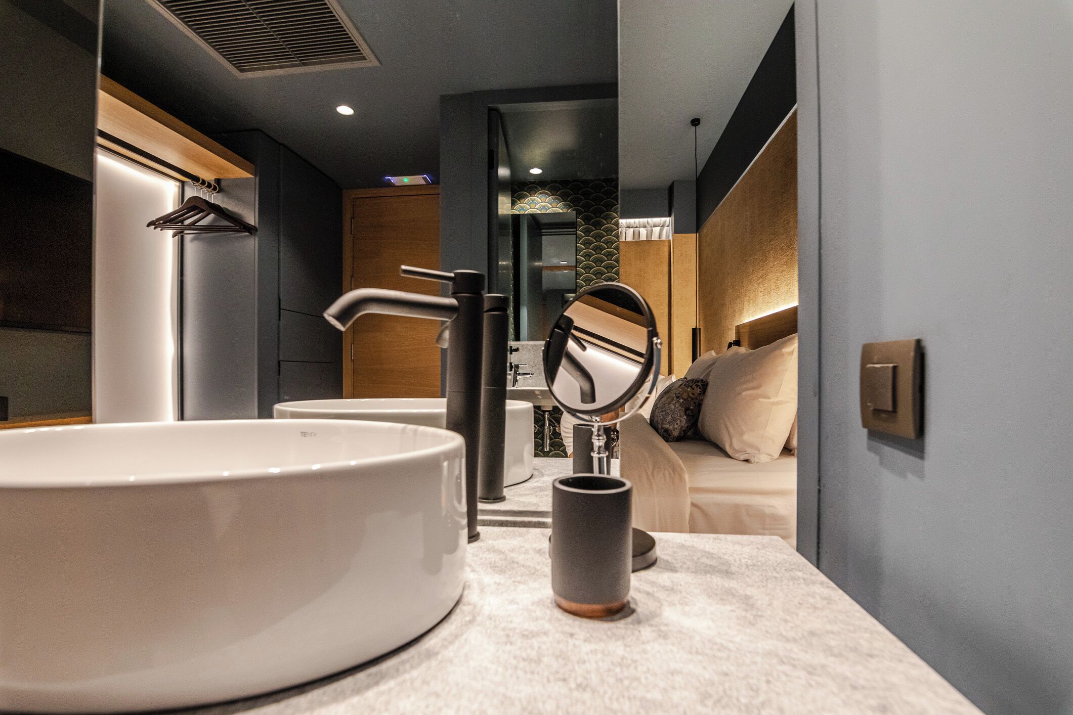 A modern bathroom with a large white sink, a mirror, and a towel rack.