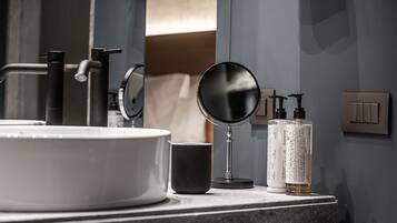 A bathroom vanity with a round mirror, a sink, and toiletries.
