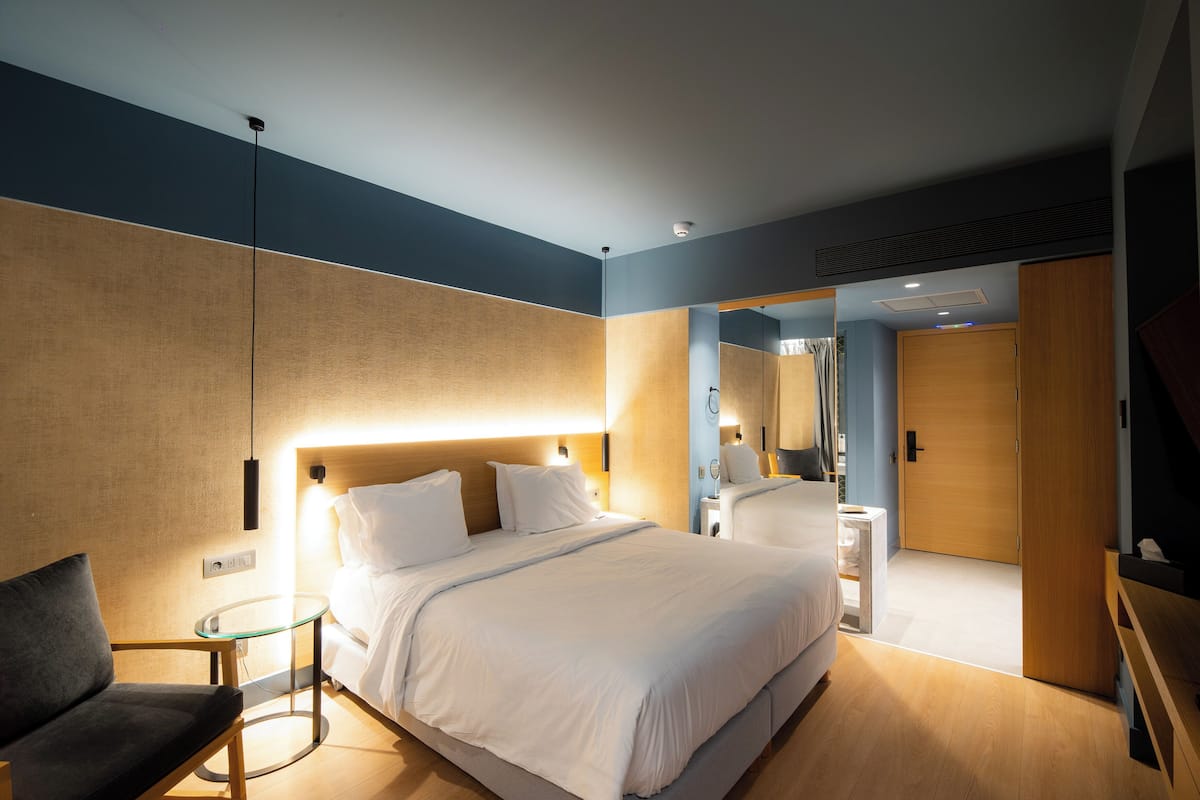Una habitación de hotel moderna con una cama grande, mesitas de noche, una zona de estar y un armario.