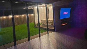 Una sala de estar moderna con un ventanal que da a un patio, un televisor de pantalla plana y una chimenea.