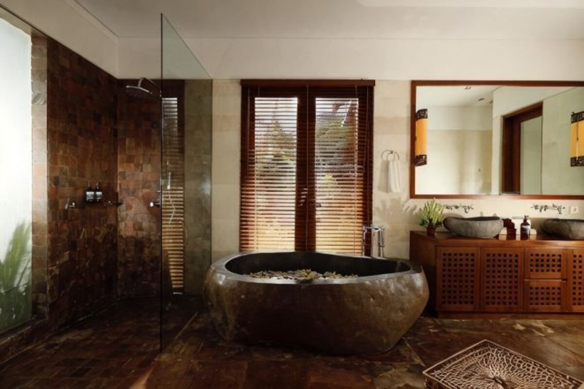 Un baño moderno con una bañera grande, cabina de ducha de vidrio y tocador de madera con espejo.