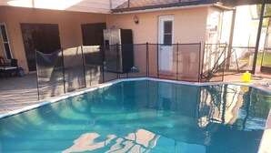 Una piscina con cerca negra y un delfín nadando en su interior.