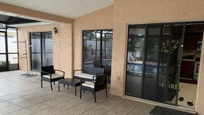 Un patio cubierto con mesa y sillas, una puerta corrediza de vidrio y vista a una piscina.