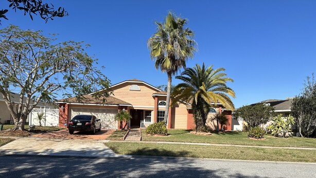 Una casa residencial con garaje, entrada para vehículos y una palmera.