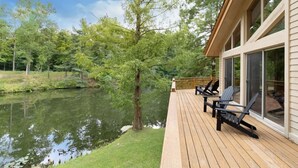 A deck with chairs overlooking a body of water, surrounded by trees.
