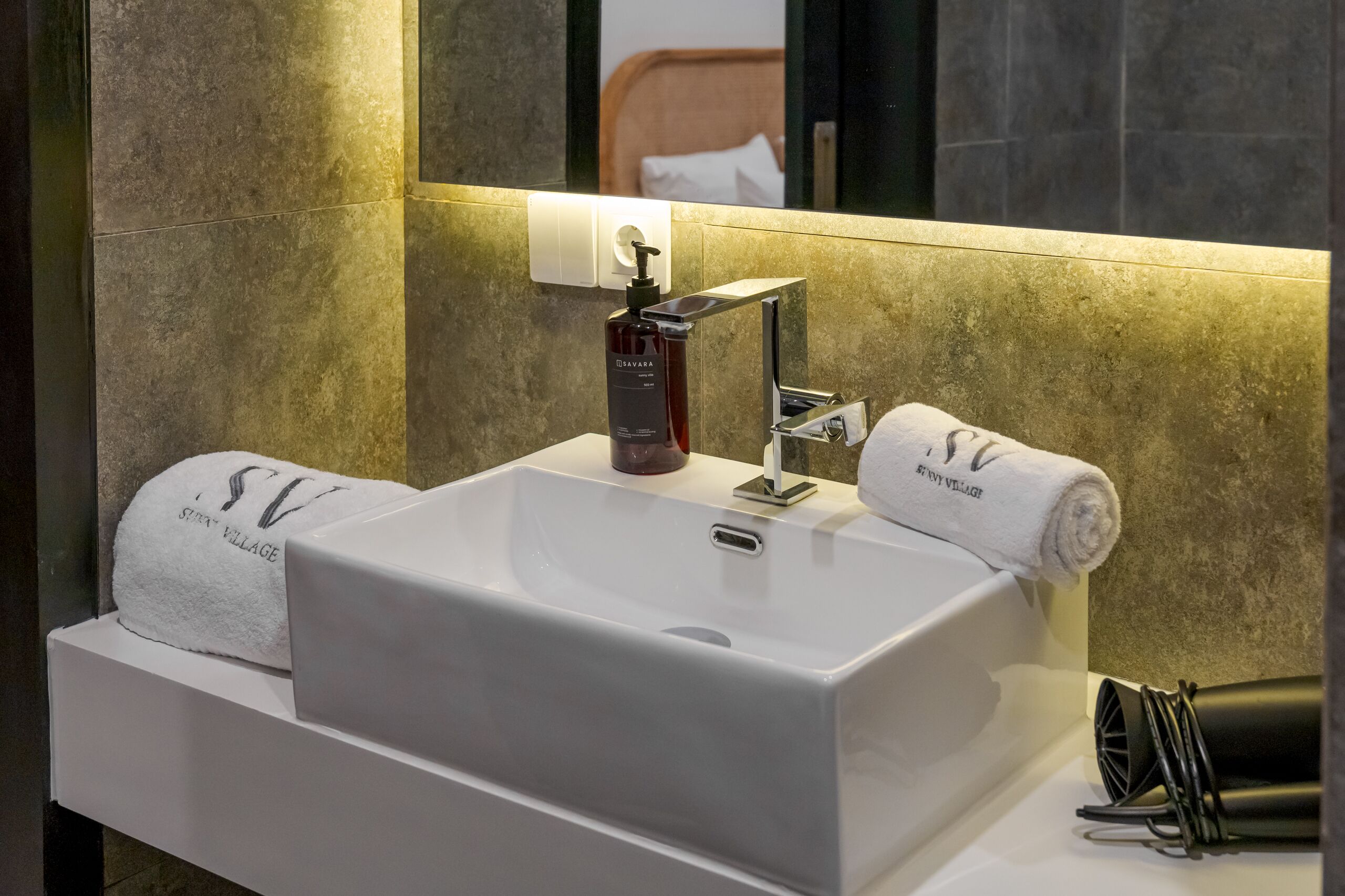 A modern bathroom with a white sink, a mirror, and a towel rack.