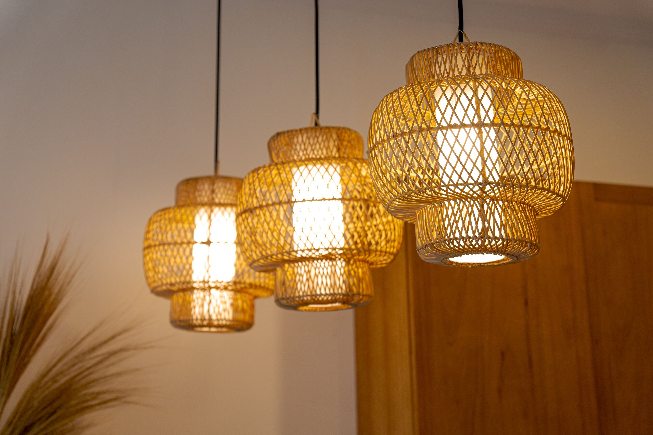Three hanging wicker lamps with a warm glow, suspended from the ceiling.