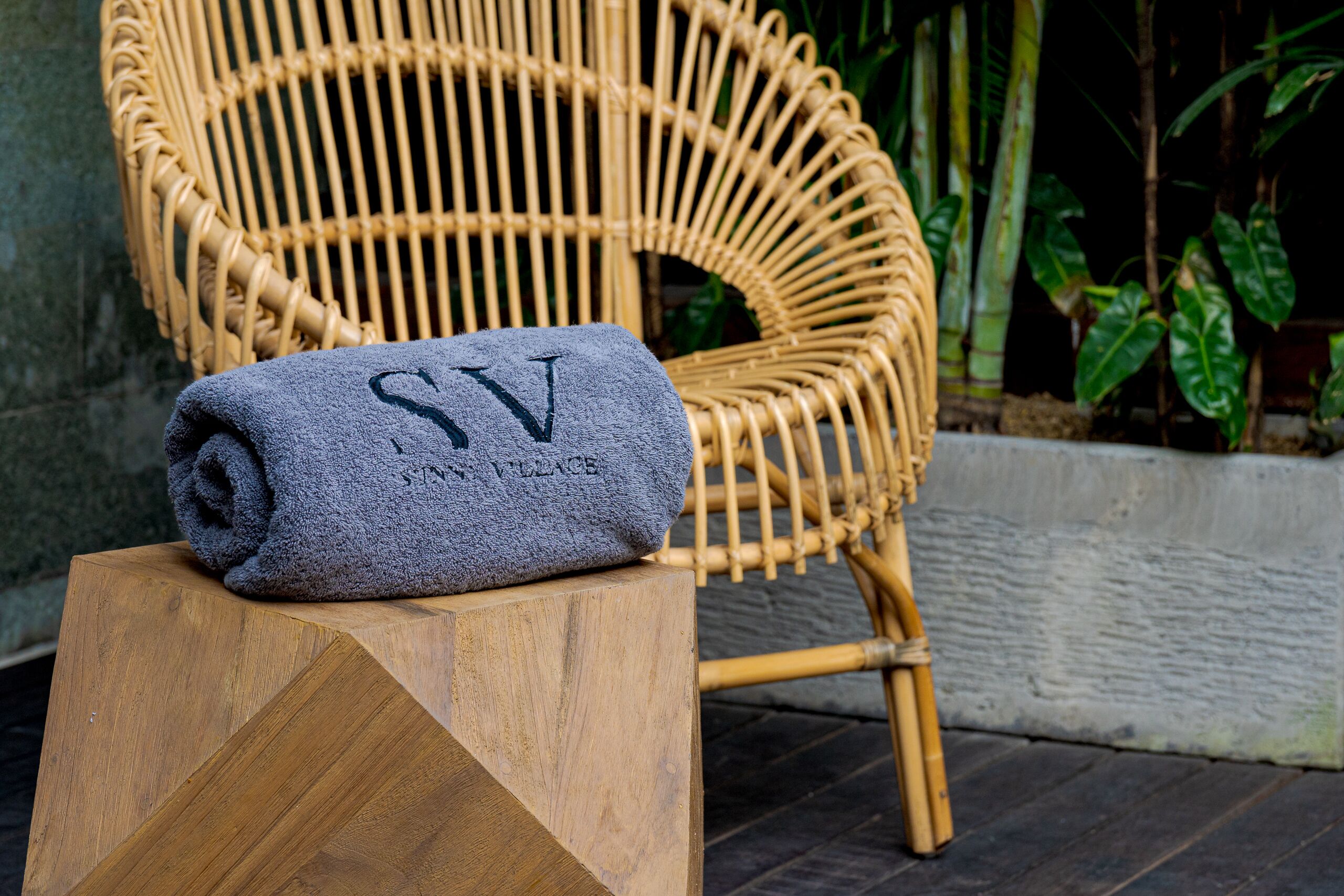 Une serviette enroulée, portant les inscriptions « SV » et « JANTVILLE », est posée sur un tabouret en bois.