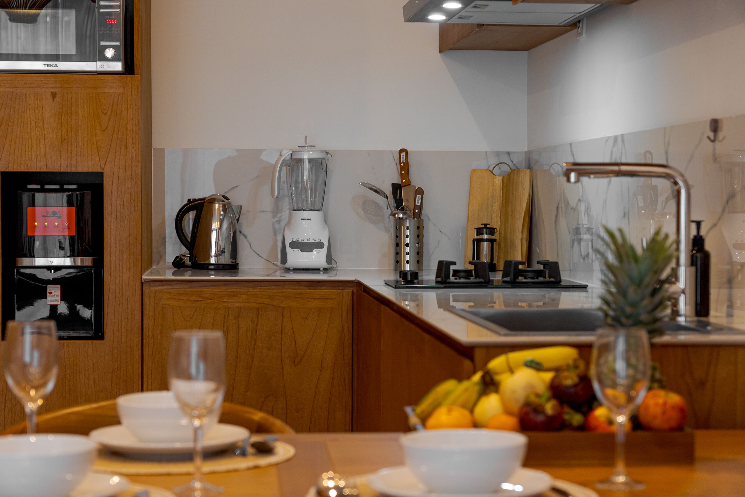 A modern kitchen with a built-in refrigerator, a coffee maker, a blender, and a wooden countertop.