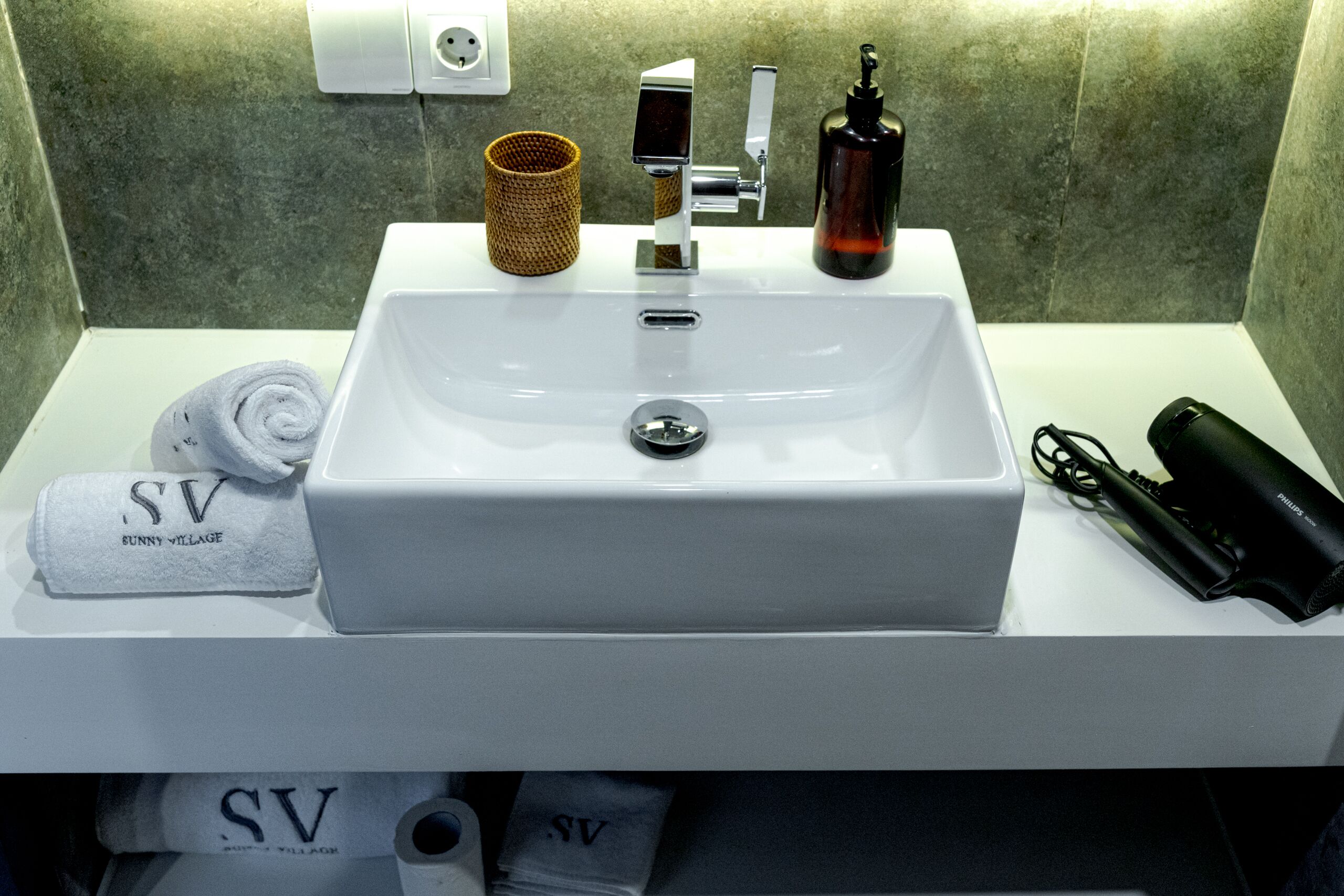 A bathroom sink with a towel, a soap dispenser, and a hairdryer.