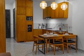 A compact kitchen with wooden cabinets, a microwave, a sink, and a dining table set for four.