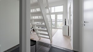 Een modern interieur met een trap die naar een balkon leidt.