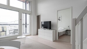 Een moderne slaapkamer met een groot raam, een flatscreen televisie, een bed en een klein nachtkastje.