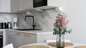 Een moderne keuken met een wit aanrecht, een roestvrijstalen spoelbak en een vaas met bloemen op de tafel.