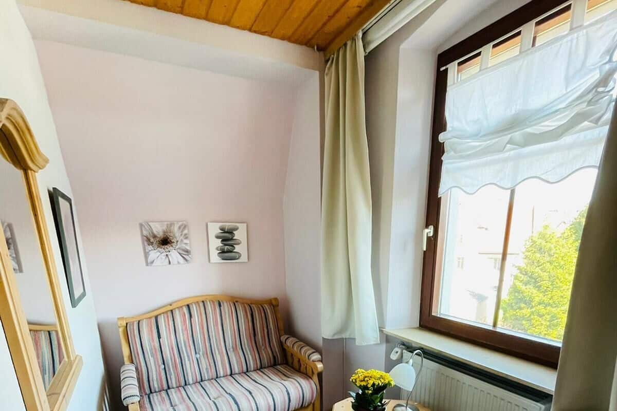 Una habitación acogedora con techo de madera, un sofá a rayas, una mesita con planta y una silla.