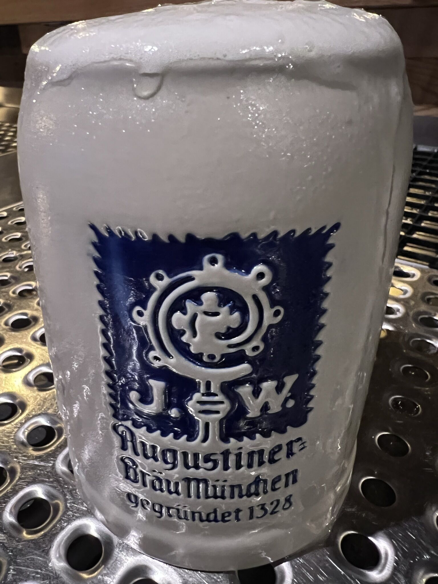 Une tasse en céramique blanche ornée d’un écusson bleu et d’une inscription.